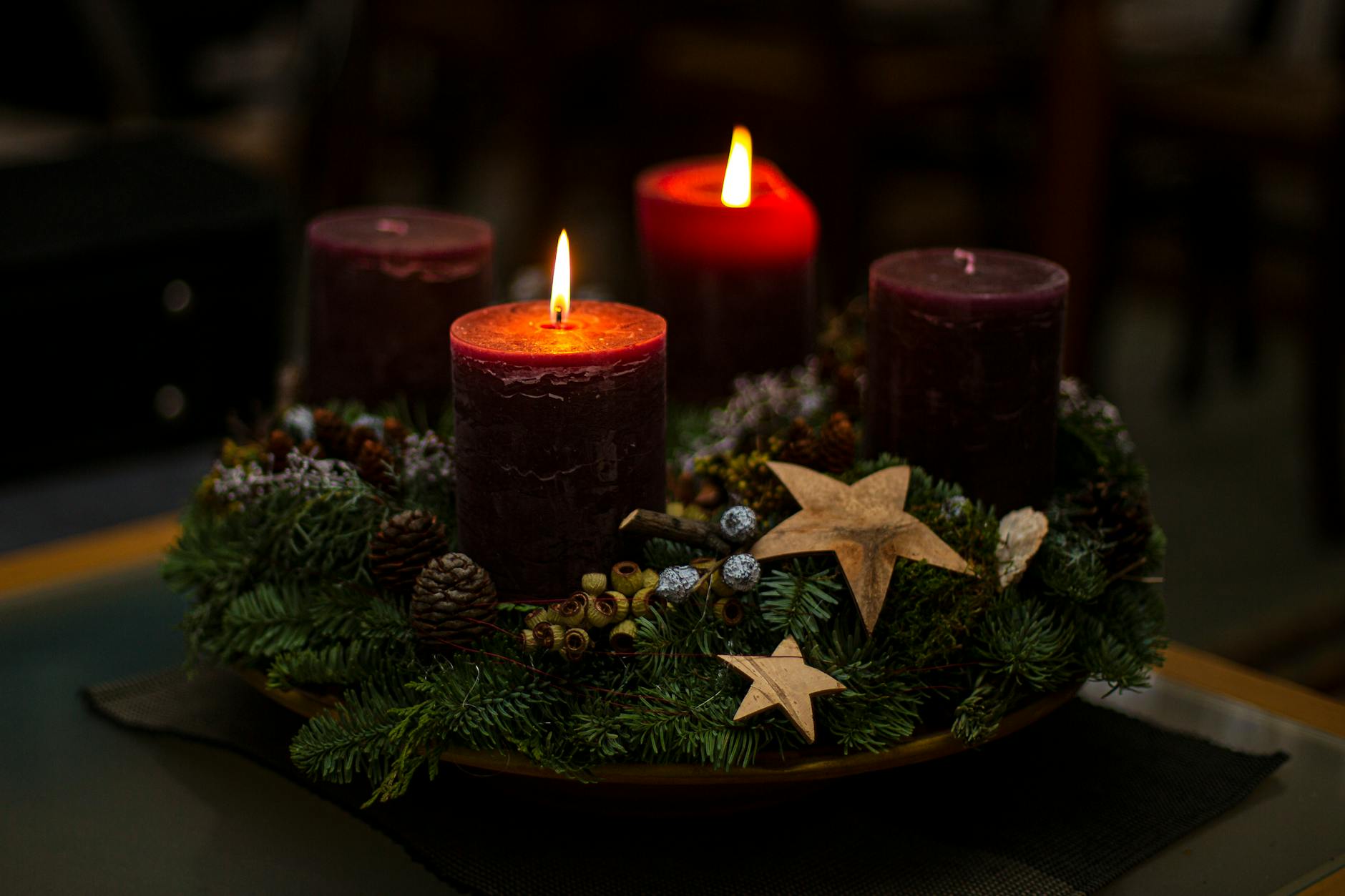 Lit candles on a decorative evergreen wreath with stars and pinecones create a cozy ambiance.