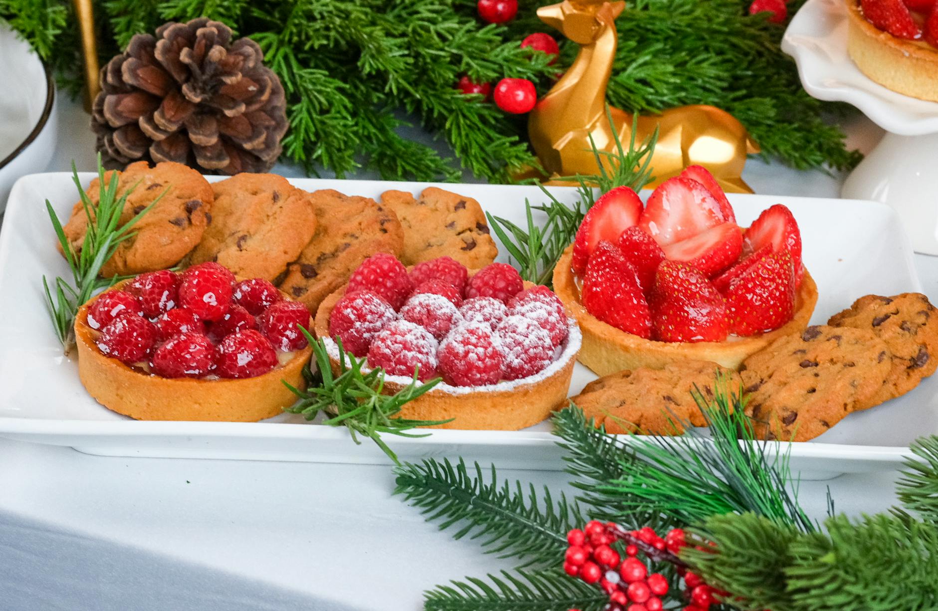 Delicious festive treat spread featuring berry tarts and cookies on a holiday table.
