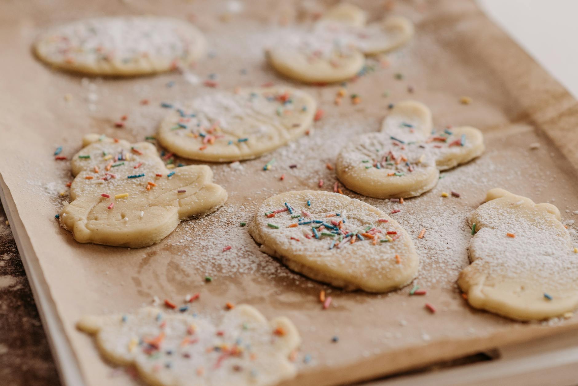 Close-up of raw cookies with sprinkles on baking parchment, ready to be baked.